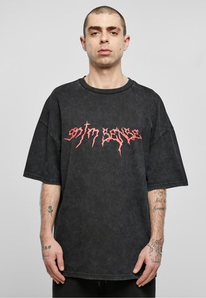 Zwart oversized T-shirt van katoen, met een verweerde textuur en rode grafische tekst in een hoekig lettertype over de borst.