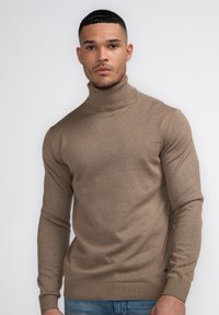 Brauner Rollkragenpullover aus einem glatten Strickstoff mit gerippten Bündchen und Saum. Verfügt über eine taillierte Form und minimalistische Details.