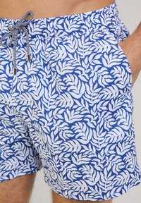 Zwemshorts in blauw met een wit bladenpatroon, elastische tailleband en trekkoord. Zijzakken en een lichte, gladde stoftextuur.