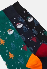 Tres pares de calcetines festivos: verdes con muñecos de nieve y árboles, azul marino con muñecos de nieve y árboles, negros con acentos coloridos. Material de mezcla de algodón.