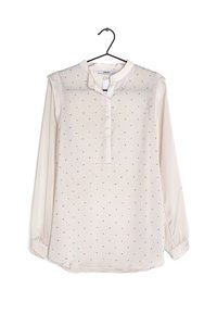 Camicetta beige chiaro a maniche lunghe con colletto alla mandarino, caratterizzata da piccoli motivi a pois neri su tutta la superficie e una chiusura con bottoni sul davanti.