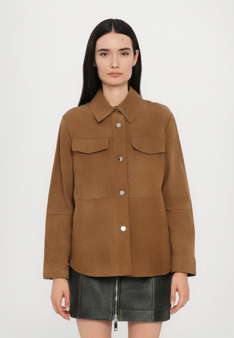 Giacca camicia in suede marrone con colletto, due tasche sul petto e bottoni argentati. Presenta maniche lunghe e orlo arrotondato.