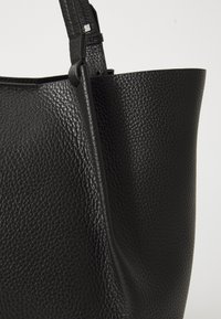 Schwarze Ledertasche mit strukturiertem Finish, featuring a structured shape und dicker Schulterriemen. Enthält ein metallisches Akzent.