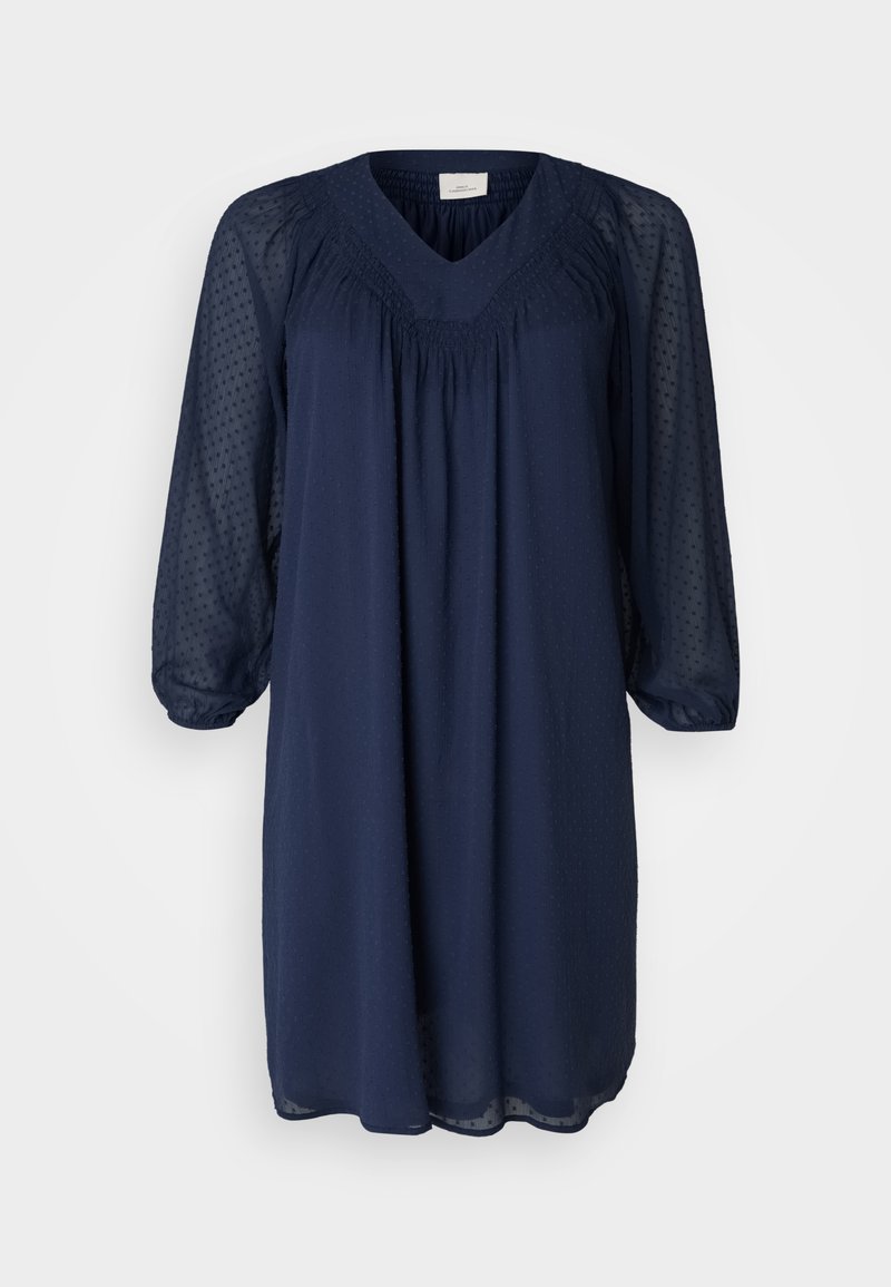 Robe bleu marine avec un décolleté en V, de longues manches en voile et des détails plissés au niveau du buste. Tissu texturé avec un motif à pois.