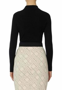 Maglione lavorato a maglia nero con maniche lunghe, design aderente, abbinato a una gonna crema a fantasia con una griglia a diamante. Tessuto liscio in tutto il capo.