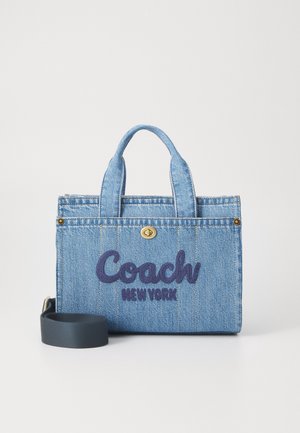Mała niebieska dżinsowa torba typu tote marki Coach z dwoma uchwytami, odpinanym czarnym paskiem oraz wyszywanym napisem "Coach New York" z przodu.
