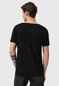 Camiseta de algodón negra con cuello redondo, mangas cortas y corte relajado, que presenta una textura suave y costuras mínimas.