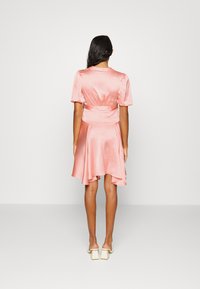 Vestido de cetim rosa com mangas puff curtas, cintura ajustada e saia rodada. Textura suave, comprimento até ao joelho e um brilho subtil.