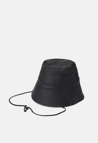 Chapéu tipo bucket preto feito de material impermeável, apresentando um design estruturado, detalhes costurados e um cordão ajustável.
