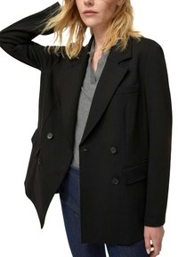 Blazer nero doppiopetto in tessuto spesso con vestibilità sartoriale. Presenta rever a lancia, due tasche frontali e bottoni decorativi.