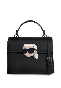 Bolso de cuero negro con forma estructurada, asa superior y correa desmontable. Presenta un personaje de dibujos animados con gafas de sol como detalle.