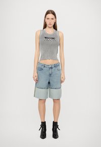 Grå ribbet croptopp med "MOSCHINO JEANS" trykk, kombinert med lyseblå denimshorts med kontrastpaneler og middels høyde.