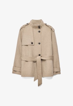 Abrigo militar color beige de lana con cuello alto, botones negros, hombreras y un cinturón a juego atado en la cintura.