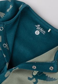 Teal and green bodysuit with dinosaur print, snap closures, and a soft, textured finish. Labeled size 62 (3 months).