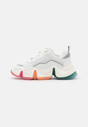 Baskets blanches épaisses avec dessus en mesh et cuir, segments de semelle multicolores en rouge, orange, vert et bleu, et fermeture à lacets.