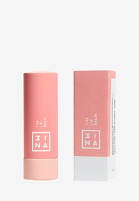 Rosa, sylinderformet leppebalsam i tube med matt finish, som har hvit tekst. Den kommer med en matchende firkantet boks som viser lignende designelementer.