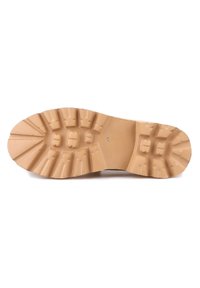 Semelle de chaussure en caoutchouc avec un motif texturé et strié. Présente de larges crampons pour l'adhérence et une couleur beige unie. Surface lisse autour des bords.