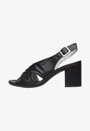Sandale en cuir noir avec un design à talon ouvert, dotée de brides entrecroisées et d'un talon épais, sur un fond neutre.