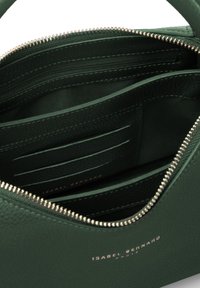 Interieur van een groene leren handtas met meerdere kaarten sleuven, een ritscompartiment en een gestructureerde afwerking. Goudkleurige ritssluiting zichtbaar.