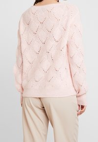 Helles rosa gestricktes Sweatshirt mit einem strukturierten Rautenmuster, locker sitzend mit gerippten Bündchen und Saum. Rückansicht.