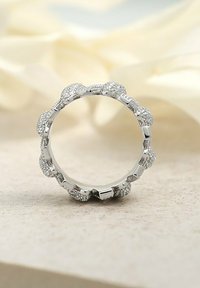 Silberner Ring mit strukturiertem Band, abgerundeten Akzenten, subtilen Funkeln und einer glatten Innenseite. Auf einem hellen Hintergrund platziert.