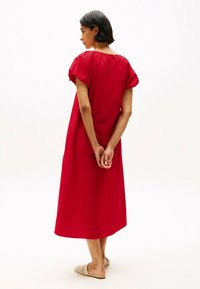 Vestido rojo hasta la rodilla con mangas cortas abullonadas y un ajuste relajado. Tela lisa, con cuello redondo y bolsillos laterales.