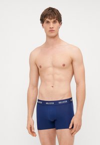 Boxeri de culoare albastru închis, cu o talie branduită, fabricați dintr-un material elastic. Design ajustat, cu o textură netedă și cusături minime.
