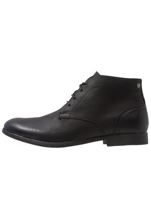 Bottine noire en cuir avec laçage sur le devant, bout arrondi lisse, talon bas empilé et détails subtils de couture.