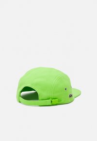 Grøn kasket med et struktureret design, justerbar rem, logo-detalje på siden og ventilationshuller nær ryggen.