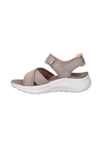 Sandale ouverte beige clair avec brides réglables, maille respirante, semelle rembourrée et semelle extérieure en caoutchouc blanche légèrement surélevée.