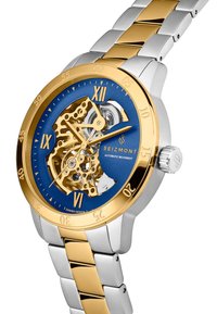 Automatisk ur med blå urtavla, guldfärgade detaljer, romerska siffermarkörer och ett tvåfärgat armband av rostfritt stål.