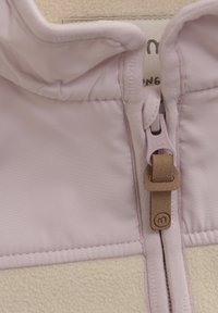 Helle pinke Fleece-Textilie mit einer strukturierten Außenfläche, ausgestattet mit einem Frontreißverschluss und einem ziehbaren Tab aus beige Leder sowie einem Innenfutter.