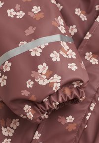 Vandafvisende stof med blomster mønster i mahogni med lyserøde og brune blomster; har påsyede elastiske manchetter og sølvreflekterende stribe.