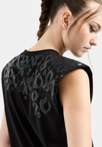 Top senza maniche nero con stampa leopardata brillante sulle spalle, realizzato in materiale morbido, con logo EA7 sul retro.