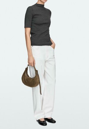 Person trägt ein dunkelgraues Kurzarmoberteil, weiße Hose, schwarze Ballerinas und hält eine braune Wildleder-Umhängetasche am Riemen.