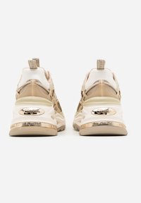 Par beige og creme chunky sneakers med tykke såler og Buffalo-logoer på hælene og trækketabber, set bagfra.