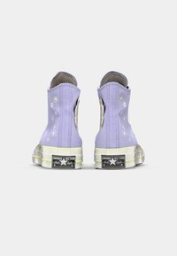 Lilac canvas high-top sneakers with floral designs, rubber soles, and contrasting yellow accents, featuring a white star logo on the heel.