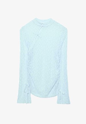Světle modrý krajkový top s dlouhým rukávem, vysokým límcem, detaily zavazování na bocích a rukávech a celoplošným texturovaným květinovým vzorem.