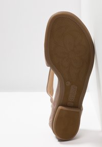 Beżowe zamszowe kobiece buty na podeszwie z teksturowanej gumy, z widocznym na pięcie wytłoczonym logo marki "Gabor" oraz wyprofilowanym kształtem.