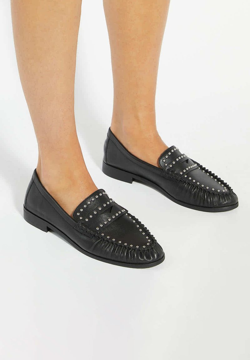 Black leather loafers with silver studs, fringe detail, flat soles, and slip-on design. Smooth texture and rounded toe shape.