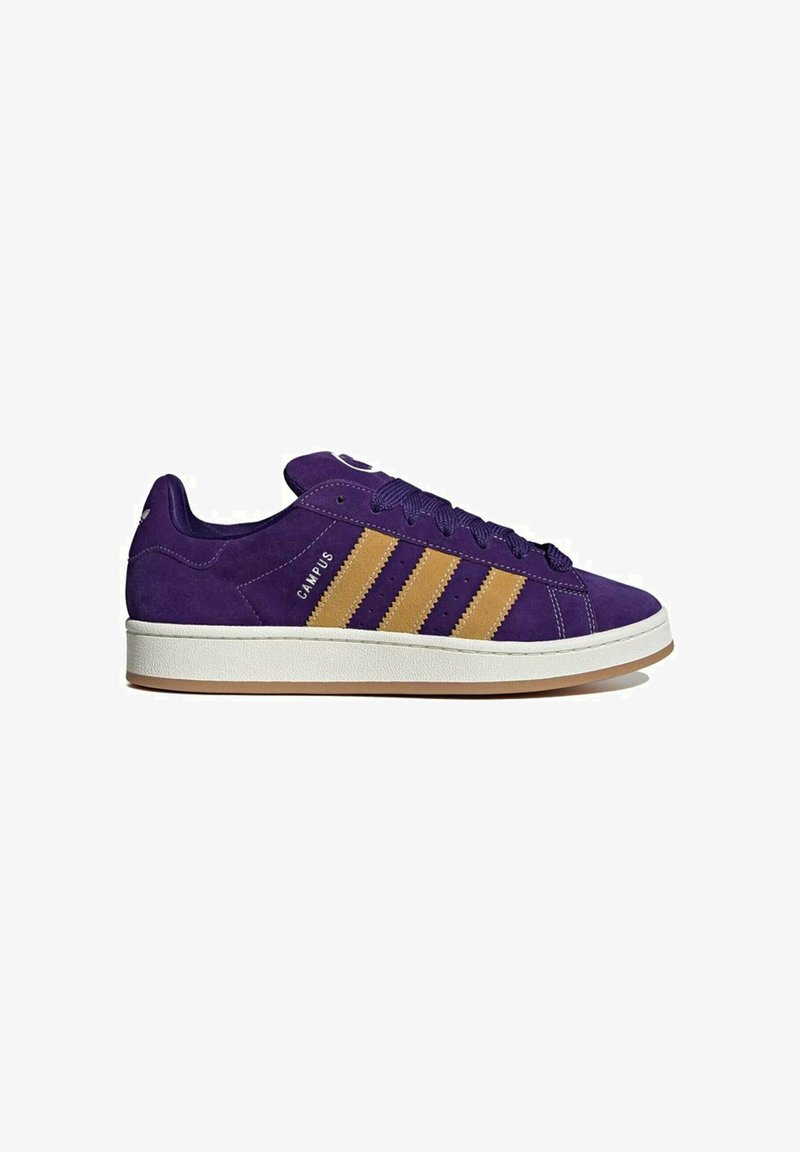 Sneaker in suede viola con tre strisce dorate, suola in gomma bianca e punta tonda. Lacci e dettagli del marchio sul lato.