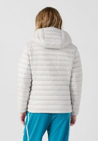 Chaqueta acolchada gris claro con capucha, que presenta un diseño acolchado y una textura suave. La vista trasera muestra una silueta ajustada y sin elementos visibles de hardware.