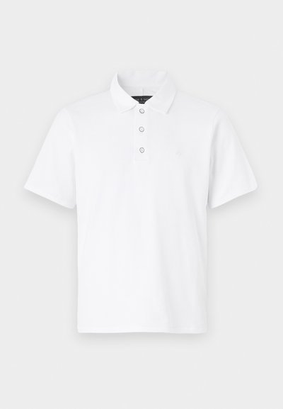 Polo shirt blanc à col, avec patte de boutonnage à trois boutons et manches courtes. Matériau en coton doux avec une texture plate.