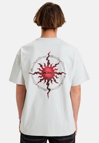 Light gray cotton t-shirt featuring a red sun graphic with black accents on the back, short sleeves, and a relaxed fit.