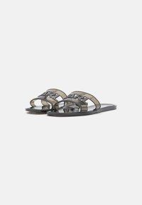 Chanclas transparentes negras con una amplia doble correa que presenta la inscripción en relieve "Karl". Suela plana con una textura suave.