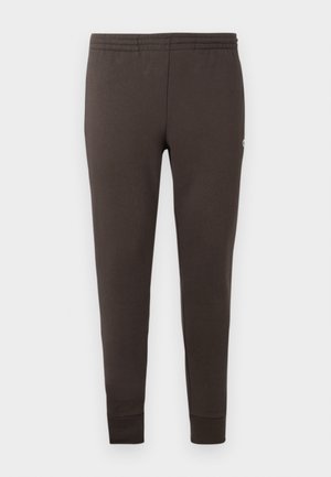 Pantalons de survêtement marron foncé en tissu doux. Dotés d'une taille élastique et de poignets fuselés. Design minimaliste sans motifs.