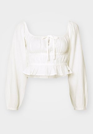 White, textured cropped top with a square neckline, long puffed sleeves, and a drawstring tie. Smocked waist with a ruffled hem detail.