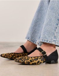 Zapatos planos de estampado de leopardo con una correa de tobillo de ante negra, punta afilada y pequeños detalles de hebilla metálica. Parte superior texturizada, tacón bajo.