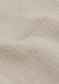 Světlý béžový texturovaný látkový materiál s jemným kostkovaným vzorem, hladkým povrchem a měkkým vzhledem. Vhodný pro různé textilní aplikace.