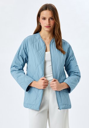 Lysblå quiltet jakke med rund halsudskæring, lynlås lukning og lange ærmer. Har et tekstureret mønster og en afslappet pasform.